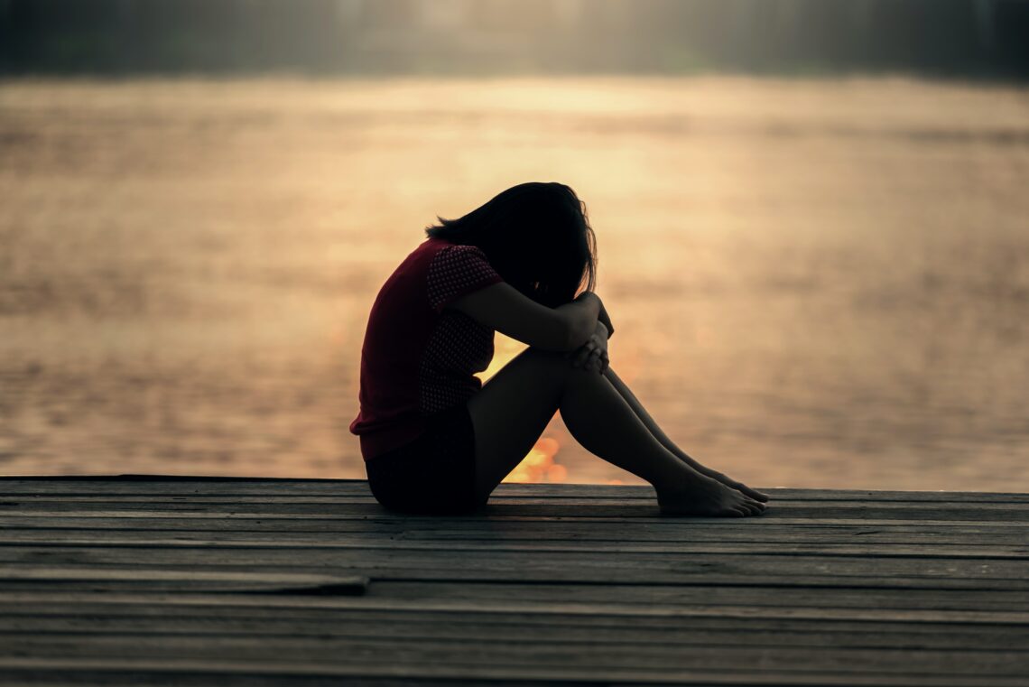 Woman sitting by water